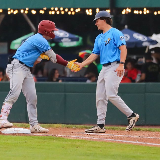 Two Starfires players high five at first base